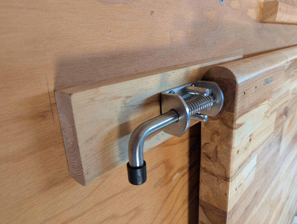 Spring-loaded retaining pin (gate latch) holding folding workbench to wall
