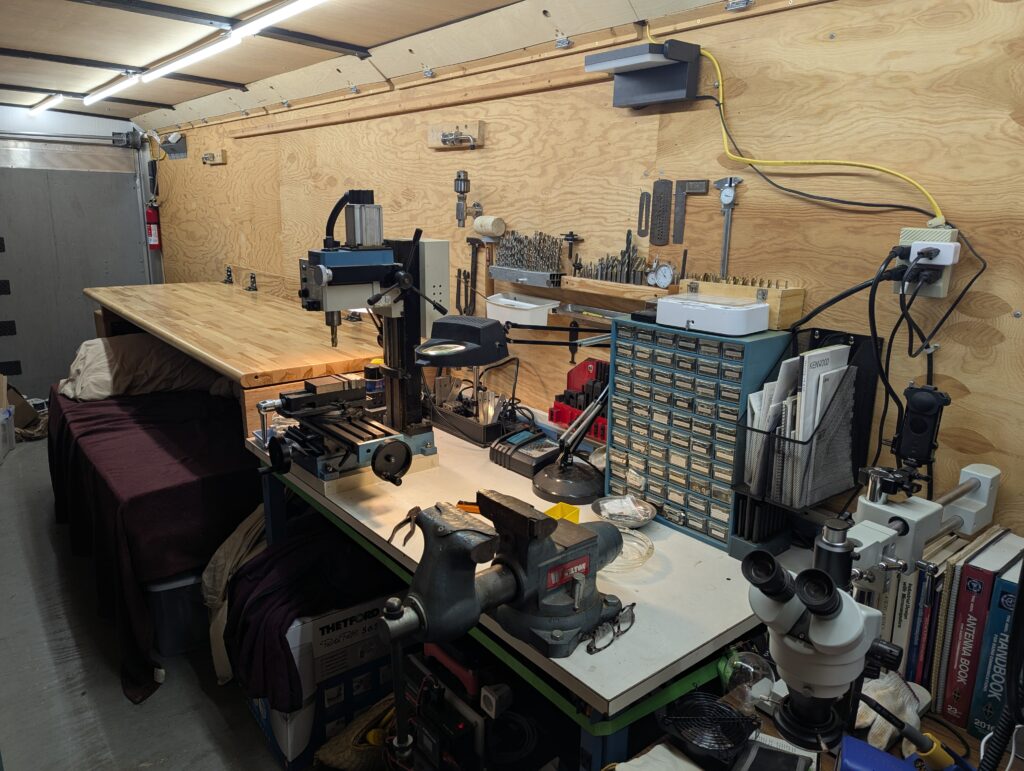 Machine table in mobile lab with small benchtop mill, vise, and other tools
